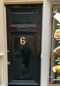 une porte noire avec le numéro 6 sur elle dans l'établissement Amsterdam Central Guest House, à Amsterdam