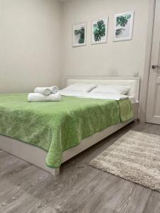 a bedroom with a large bed with a green blanket at Sun City apartment 1 in Sochi