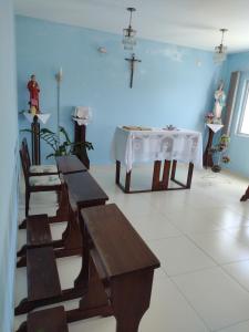 瓜拉圖巴的住宿－Stela Maris，一间设有长椅和桌子的房间,墙上有十字架