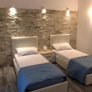 a bedroom with two beds and a brick wall at B&B Aly&Emy in Limpiddu