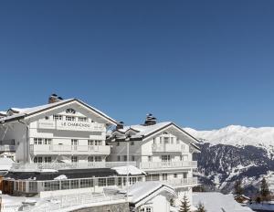 Un grand hôtel blanc avec des montagnes enneigées en arrière-plan dans l'établissement Hotel Le Chabichou, à Courchevel