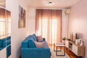 a living room with a blue couch and a window at Harizma apartmani in Kragujevac