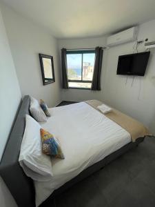 une chambre avec un grand lit blanc avec une fenêtre dans l'établissement נופש כנרת מגדלי המלכים, à Tibériade