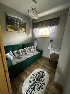 a living room with a green couch and a window at Apartamentylove - Apartament u Janicka, 100m do Krupówek in Zakopane