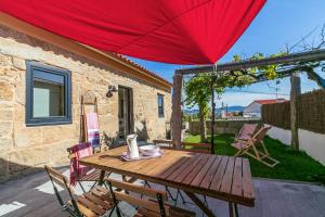 a wooden table and chairs on a patio with a red umbrella at La casita de Canido in Oya