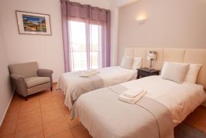 two beds in a room with a chair and a window at Nortada Suite Beach Apartment T2 in Lagos