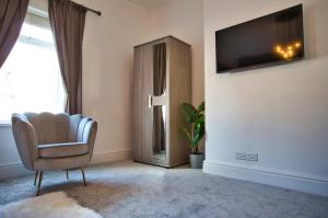 a living room with a chair and a television on a wall at Birches House in Ford Green