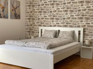 uma cama branca num quarto com uma parede de tijolos em Apartman Sunny em Sombor
