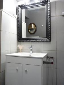 een badkamer met een witte wastafel en een spiegel bij LE LOGIS DU PALAIS in Marseille