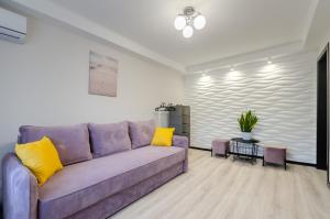 een woonkamer met een paarse bank en gele kussens bij ARTAL Apartment on Obolonskyi Avenue 16 in Kiev