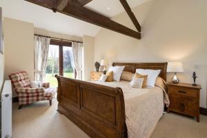 a bedroom with a large bed and a chair at The Old Stables in Yeovil