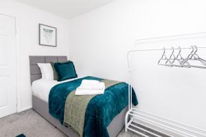 a white bedroom with a bed with a blue blanket at Lark Rise Apartment- 3BR in Ifield