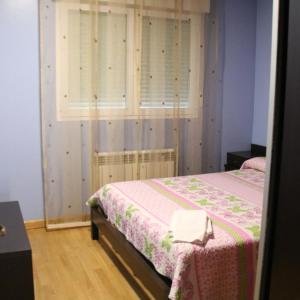 1 dormitorio con 1 cama con manta rosa y blanca en HOSTAL BURGALES, en Milagro