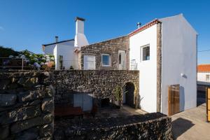 a stone house with a stone wall and a building at Casa do Simão in Nordeste