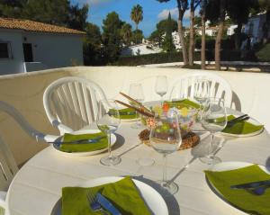 una mesa con 2 sillas y una mesa con copas de vino en Calle Alberca 5, Villotel. Madroñal Urb., 03726 Benitachell,, en Teulada