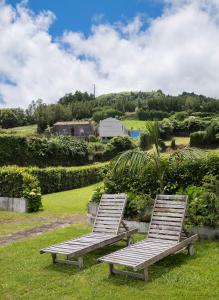 two wooden lounge chairs sitting in the grass at Casa do Simão in Nordeste