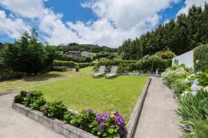 a garden with two park benches and flowers at Casa do Simão in Nordeste