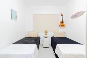 two beds in a room with a guitar on the wall at GB37 Excelente Apt 2 Suítes em Guarajuba in Guarajuba
