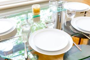 una mesa de cristal con platos blancos y vasos. en Bright & Comfortable Angel Apartment en Londres
