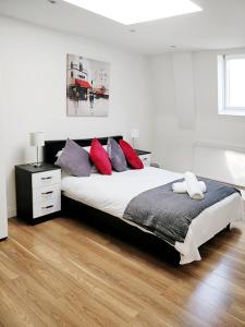ルートンにあるCavendish Apartmentのベッドルーム1室(大型ベッド1台、赤と紫の枕付)