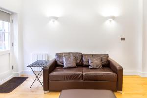 a brown leather couch in a living room with a table at Bright & Comfortable Angel Apartment in London