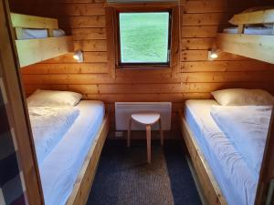 two beds in a log cabin with a table and a window at Höfn Cottages in Höfn