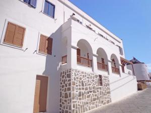 a white building with arches and windows on it at The Windmill in Ios Chora