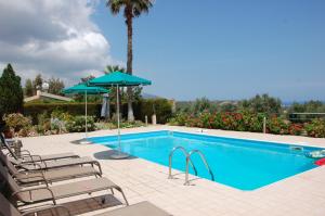 a swimming pool with chairs and umbrellas next to it at Villa Chrysanthia in Polis Chrysochous