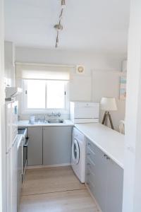 a white kitchen with a sink and a dishwasher at Kypkeys Apartments in Voroklini