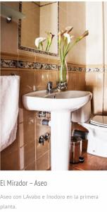 ein Badezimmer mit einem weißen Waschbecken mit einer Blumenvase in der Unterkunft El Mirador 3 in Alcalá del Júcar