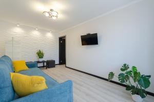 uma sala de estar com um sofá azul e uma televisão em ARTAL Apartment on Obolonskaya Square 1 em Kiev