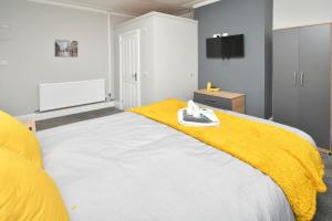 a bedroom with a bed with a yellow blanket on it at Townhouse @ Bucknall New Road Stoke in Hanley