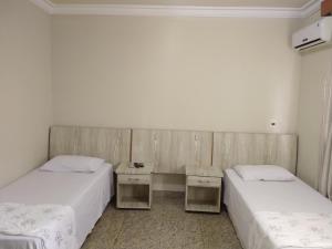 two beds in a room with two tables at Crystal Plaza Hotel Marista in Goiânia