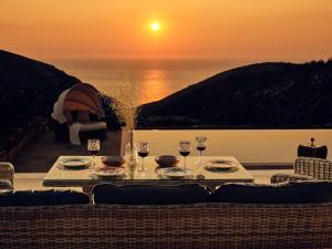 - une table avec des verres de vin et une vue sur l'océan dans l'établissement Karousa Villa - Karousa Villas Anafonitria Zakynthos, à Anafonítria