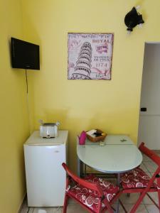 una pequeña cocina con nevera, mesa y sillas en GIGIOTTO, en Siracusa