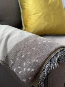 a gray blanket on a couch with a yellow pillow at The Bakehouse in Kelso