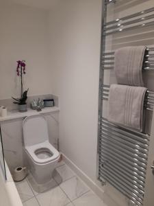 a bathroom with a white toilet and towels at Beautiful Double Bedroom- In a modern 2 bed shared house in Chigwell