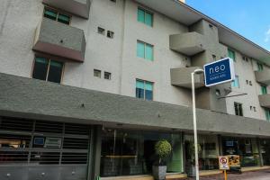 un grand bâtiment avec un panneau devant lui dans l'établissement Neo Business Hotel, à Culiacán