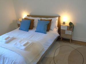 a large white bed with blue pillows in a bedroom at Snug - Tearlag Apartment in Helensburgh