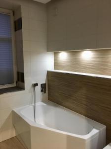 a white bath tub in a bathroom with a window at kameralny apartament II in Olsztyn