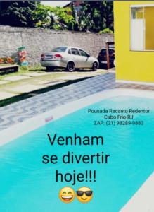 un cartel de un hotel con un coche aparcado junto a una piscina en Recanto Redentor, en Cabo Frío