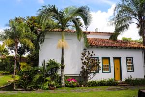 uma casa branca com uma palmeira em frente em Pousada do Barão em Santa Rita do Sapucaí
