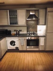 uma cozinha com um fogão e uma máquina de lavar roupa em ochiltree apartment em Glasgow