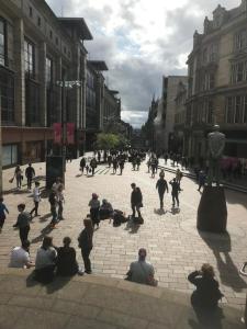 a group of people sitting on a city street at ochiltree apartment in Glasgow