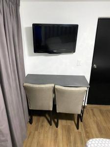 une table avec deux chaises et une télévision murale dans l'établissement Hotel Olé, à Monterrey