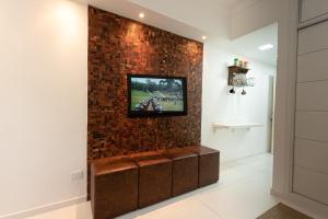 a television on a brick wall in a room at Aparts -Hotel Cavalinho Branco in Águas de Lindóia