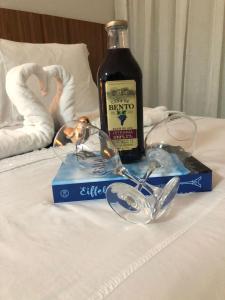 a bottle of wine and glasses on a bed at Magnífico APARTAMENTO de Charme - 3 quartos AR CONDICIONADOS SPLIT - Beira Mar, 2 banheiros, 2 vagas garagem, 4 varandas, 2 elevadores, Redes para descanso, Wi-Fi, Air Fryer, Disney Plus, Star Plus, HBO Max, Guarda Sol, Cadeiras de Praia e Caixa Térmica in Guarapari