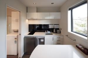 a small kitchen with white cabinets and a window at Little Rock in Lake Tekapo