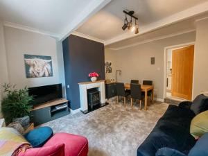 ein Wohnzimmer mit einem Sofa und einem Tisch mit einem Kamin in der Unterkunft LITTLE RED HOLIDAY HOME - 2 Bed House with Free Parking within West Yorkshire, local access to the Peak District in Halifax