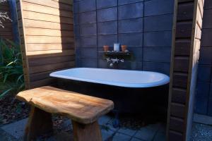 a bath tub and a wooden bench in a bathroom at Designer Cabin - Lake Tekapo in Lake Tekapo
